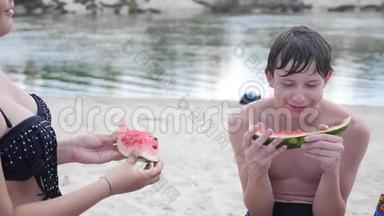 孩子们，青少年在海滩上休息，笑着<strong>吃西瓜</strong>，慢动作<strong>视频</strong>。 男孩和生活方式女孩